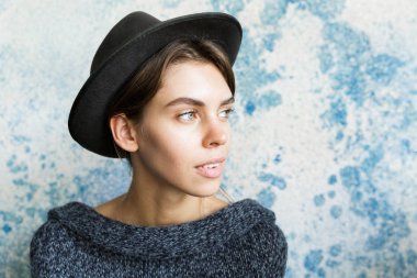 Kadar uzağa arıyorsunuz mavi duvar arka plan üzerinde kazak ve şapka giymiş güzel bir genç kadının portresi kapatın