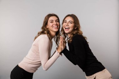 Görüntü iki neşeli kadın gülüyor ve birlikte poz gri arka plan üzerinde izole