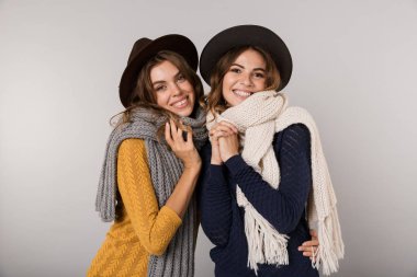 Şapka ve gri arka plan üzerinde izole kamera gülümseyen tulum giyen iki beyaz kadın görüntüsünü