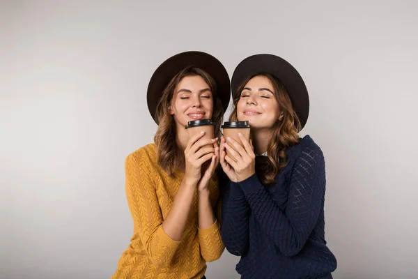 Obrázek Dvou Hezké Ženy Nosit Klobouky Drží Sebou Kávu Izolované — Stock fotografie