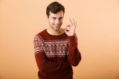 Portre ok jest gösterilen bej renkli arka plan üzerinde izole bir gülümseyen genç adam ayakta