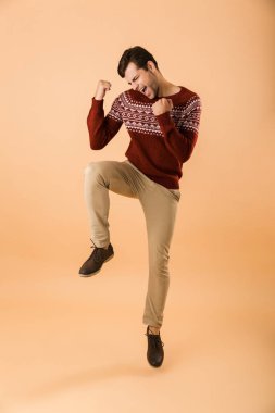 Beyaz adamla 20s tam boy görüntü kıl bej renkli arka plan üzerinde izole yumruk kenetlenmesi giyen örme kazak