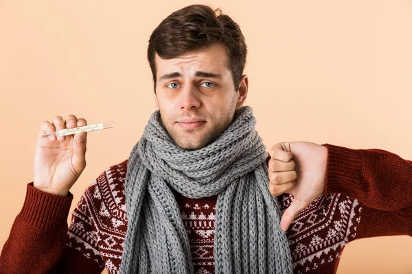 남자의 스웨터에 베이지색 스카프 아래로 온도계 엄지손가락을 보여주는 초상화 — 스톡 사진