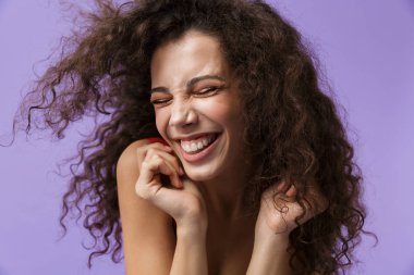 Görüntü çok mutlu kadın 20'li yaşlarda giyen kırmızı elbise gülen ayakta menekşe arka plan üzerinde izole