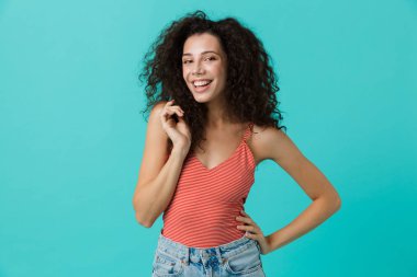 Görüntü güzel kadın 20'li yaşlarda giyiyor rahat giyim üzerinde mavi arka plan izole ayakta gülüyor