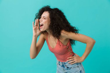 Çığlık ya da mavi arka plan üzerinde izole ayakta arayıp neşeli kadın 20'li yaşlarda giyiyor rahat giyim görüntü