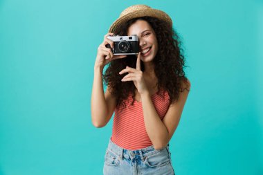 Güzel kadın 20'li yaşlarda giyen hasır şapka üzerinde mavi arka plan izole retro kamera çekim portre