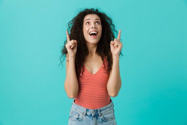 Genç kadının üzerinde mavi arka plan ayakta boşaltmak yukarı doğru parmakları işaret casual giyim 20s izole görüntü