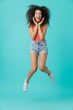 Tam boy görüntü gülümseyen ve mavi arka plan üzerinde izole atlama neşeli kadın 20'li yaşlarda giyiyor rahat giyim