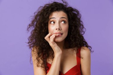 Siyah kıvırcık saçlı kapsayan yüz uzaklıkta seyir el ile menekşe arka plan üzerinde izole kırmızı elbise ile sürpriz bir kadın portresi kadar yakın
