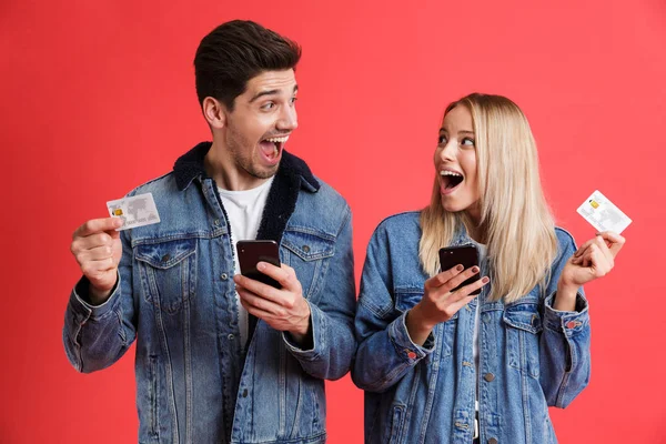 Porträt Eines Aufgeregten Jungen Paares Jeansjacken Das Isoliert Vor Rotem — Stockfoto