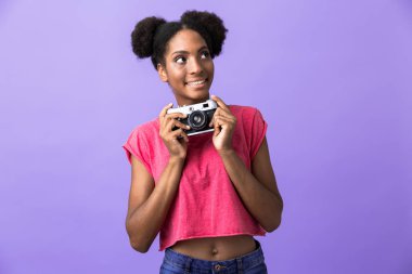 Gülümseyen ve menekşe arka plan üzerinde izole retro kamera tutarak şirin Afrikalı-Amerikalı kadın fotoğrafı