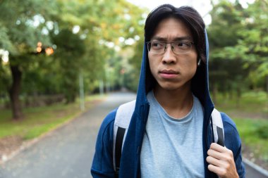 Görüntü güzel Asyalı adam giyim ve gözlük bir kenara yeşil park boyunca yürürken arıyorsunuz