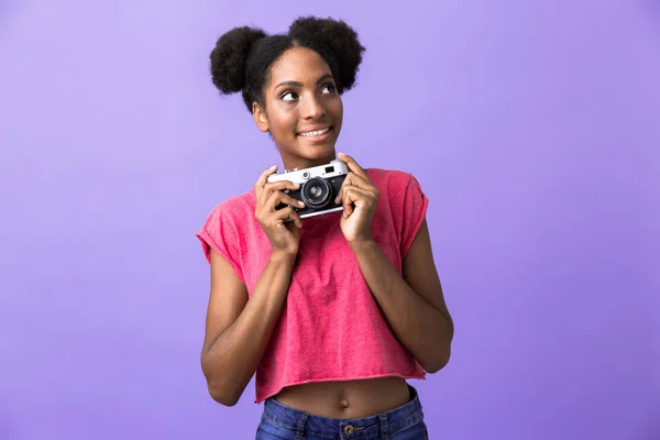 笑みを浮かべて 紫色の背景に分離された レトロなカメラを持ってかわいいアフリカ系アメリカ人の女性の写真 — ストック写真