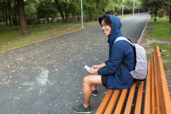 Sonriente Joven Asiático Vestido Con Sudadera Con Capucha Sentado Banco —  Fotos de Stock