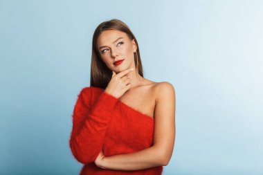 Uzağa arıyorsunuz düşünme, mavi arka plan üzerinde izole kazak ayakta giyen güzel genç kadın