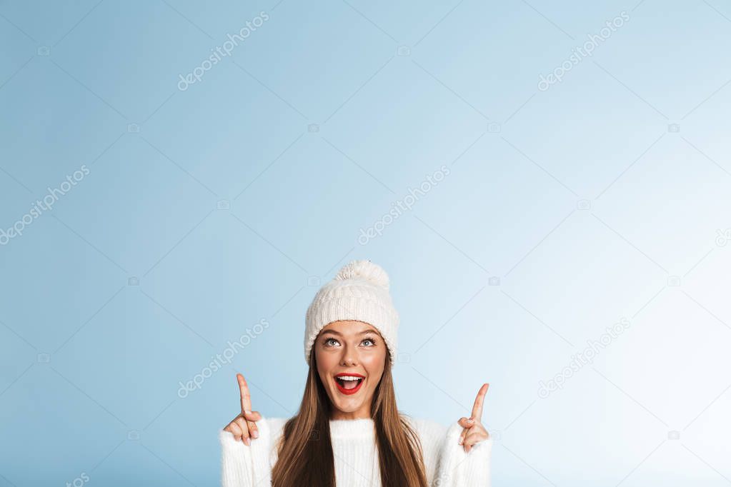 Image of a beautiful cute amazing young woman wearing winter hat posing isolated over blue wall background showing copyspace.