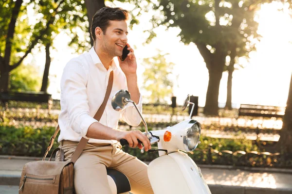 携帯電話で話しているスクーターで野外を歩いているハンサムな若いビジネスマンのイメージ — ストック写真