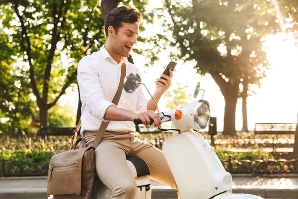 Jovem Empresário Alegre Sentado Uma Moto Livre Usando Telefone Celular — Fotografia de Stock