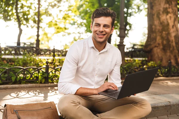 Fröhlicher Junger Geschäftsmann Sitzt Draußen Und Arbeitet Laptop — Stockfoto