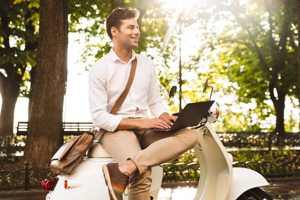 Vrolijke Jonge Zakenman Zittend Een Motorfiets Buitenshuis Werkt Laptopcomputer — Stockfoto