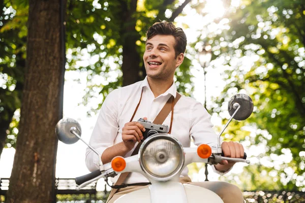 stock image Happy young businessman riding on a motorbike outdoors, taking pictures with a photo camera