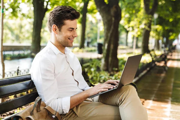陽気な青年実業家屋外に座って ノート パソコンに取り組んで — ストック写真