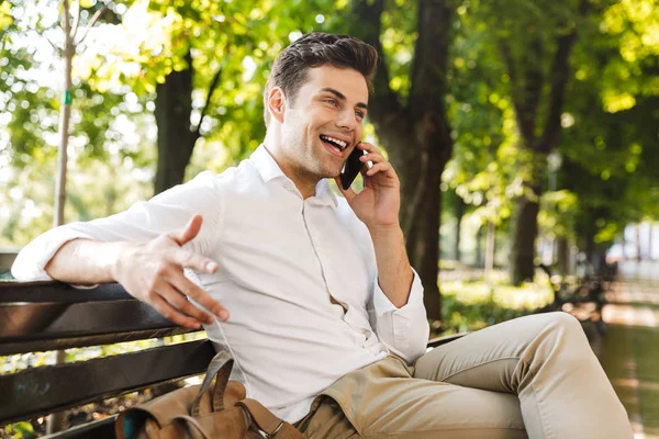 Cep Telefonu Üzerinde Konuşurken Açık Havada Bankta Oturan Mutlu Genç — Stok fotoğraf