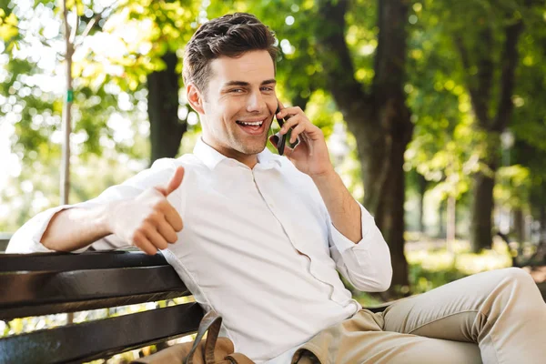 Cep Telefonu Üzerinde Konuşurken Açık Havada Bankta Oturan Mutlu Genç — Stok fotoğraf