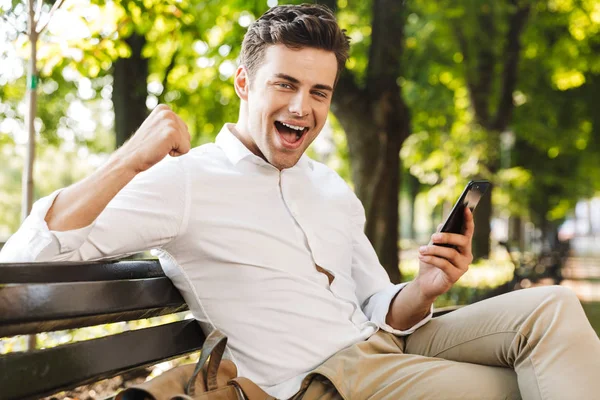 Boldog Fiatal Üzletember Egy Padon Szabadban Mobiltelefont Tartó Siker Ünneplése — Stock Fotó