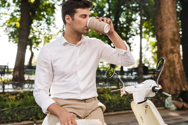 幸せな青年実業家バイク屋外に座って 新聞を読んだり コーヒーを飲みながら — ストック写真