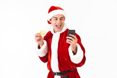 Yakışıklı adam 30'lu holding smartphone ve kredi kartı Studio beyaz arka plan üzerinde izole Noel Baba kostümlü resmini