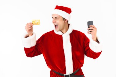 İyimser adam 30'lu yaşlarda cep telefonu ve kredi kartı Studio beyaz arka plan üzerinde izole tutan Noel Baba kostümlü resmini