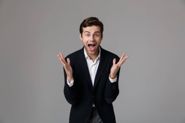 Duygusal işadamı 30'lu çığlık ve gri arka plan üzerinde izole kollu el hareketi resmi kıyafetli görüntüsünü