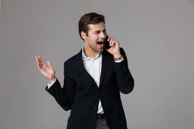 Beyaz adamın 30'lu yaşlarda iş uymak izole gri arka plan üzerinde siyah cep telefonuyla görüntü