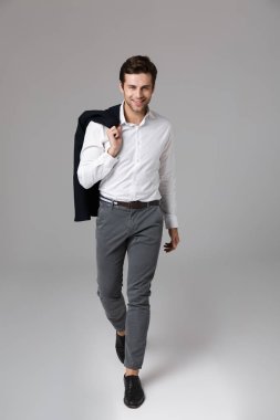 Tam boy görüntü başarılı işadamı gri arka plan üzerinde izole omzunun üzerinden yürüyüş ve holding 30s ceket