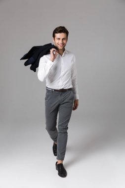 Tam boy görüntü iyimser işadamı gri arka plan üzerinde izole omzunun üzerinden yürüyüş ve holding 30s ceket