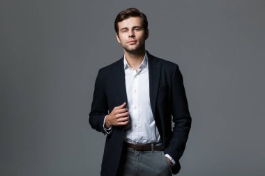 Gri arka plan üzerinde ciddi iş adamı 30'lu kameraya seyir siyah ceketli görüntü izole