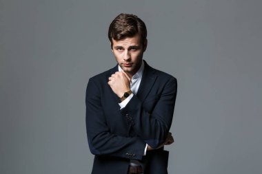 Gri arka plan üzerinde siyah ceketli kameraya bakarak konsantre işadamı 30'lu görüntüsünü izole