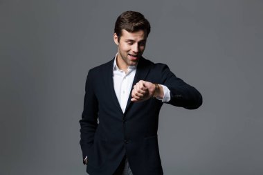 Yakışıklı bir genç işadamı portresi onun kol saati görünümlü gri arka plan üzerinde izole takım elbise giymiş