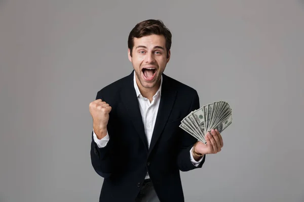 喜びに満ちたビジネスマン 代スーツ笑顔と灰色の背景上分離された現金お金のファンを保持しているのイメージ — ストック写真