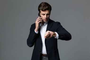 Cep telefonuyla konuşurken gri duvar arka plan üzerinde izole bir yakışıklı genç iş adamı görüntüsü.
