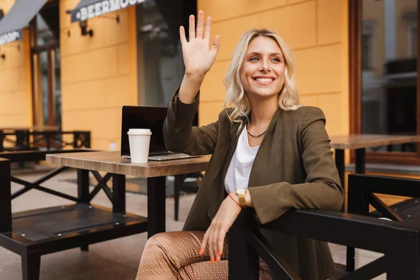 Retrato Mujer Joven Elegante Agitando Mano Lado Mientras Trabaja Ordenador —  Fotos de Stock