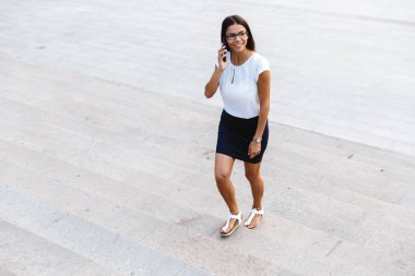 Açık havada cep telefonuyla konuşurken yürüyüş inanılmaz güzel iş kadın görüntüsünü.