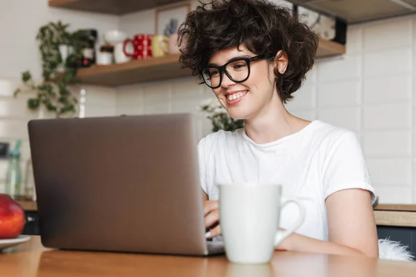 Mutlu Bir Genç Kadın Kapalı Dizüstü Bilgisayar Kullanan Mutfak Oturma — Stok fotoğraf