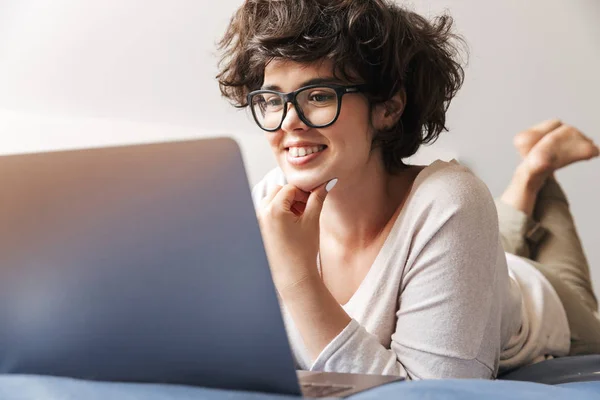 Image Happy Young Woman Lies Indoors Bed Using Laptop Computer — Stock Photo, Image