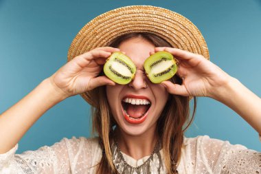 Mutlu bir güzel kadının poz görüntü üzerinde mavi duvar arka plan kivi ile izole.