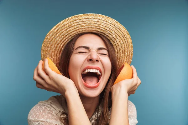 一个快乐的兴奋的漂亮的女人的形象摆在蓝色墙壁背景被隔绝与橙色柑橘作为耳机 — 图库照片