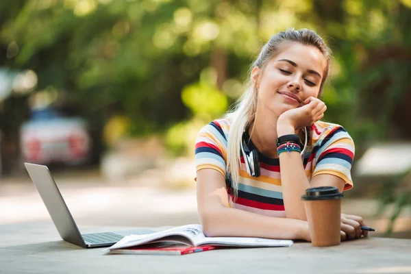 Dizüstü bilgisayar kullanan parkta oturan bir mutlu genç Sevimli kız öğrencinin görüntü.