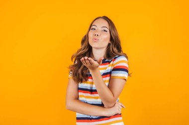 Sevimli Genç kız öpücük sarı duvar arka plan üzerinde poz görüntü.